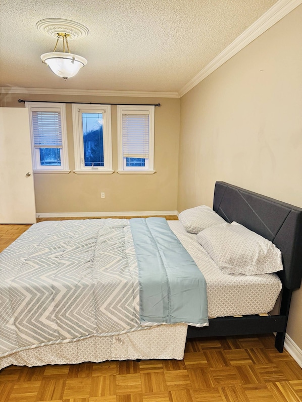 A bedroom with a bed, a window, and a ceiling light fixture.