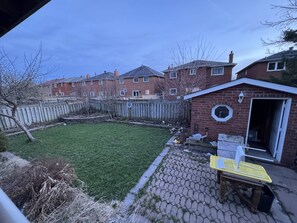 A residential backyard with a paved patio area, a small shed, and a fenced yard.