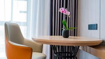 A modern room with a round table, a single chair, and a potted orchid.