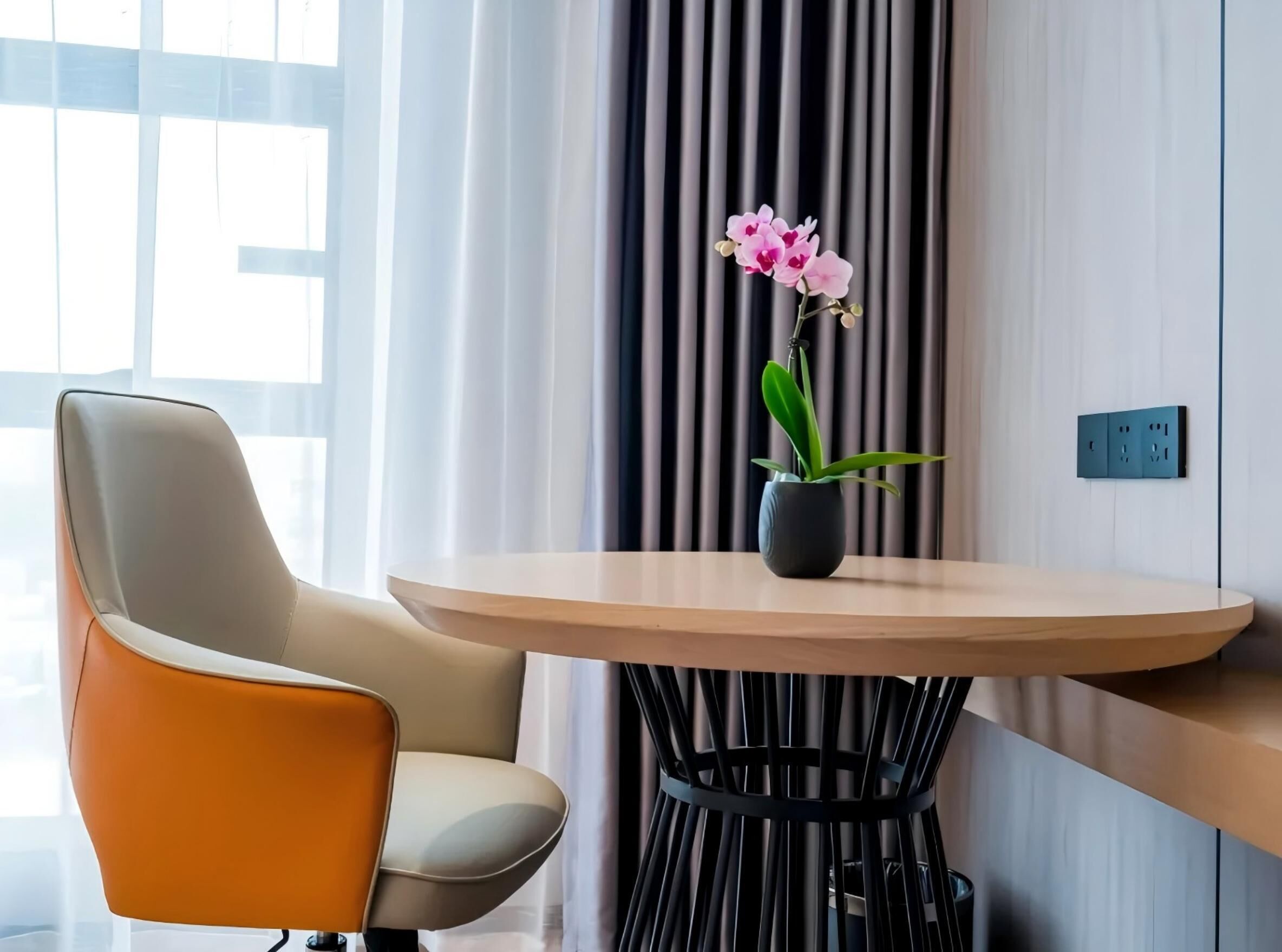 Een moderne kamer met een ronde tafel, een stoel en een potorkidee.