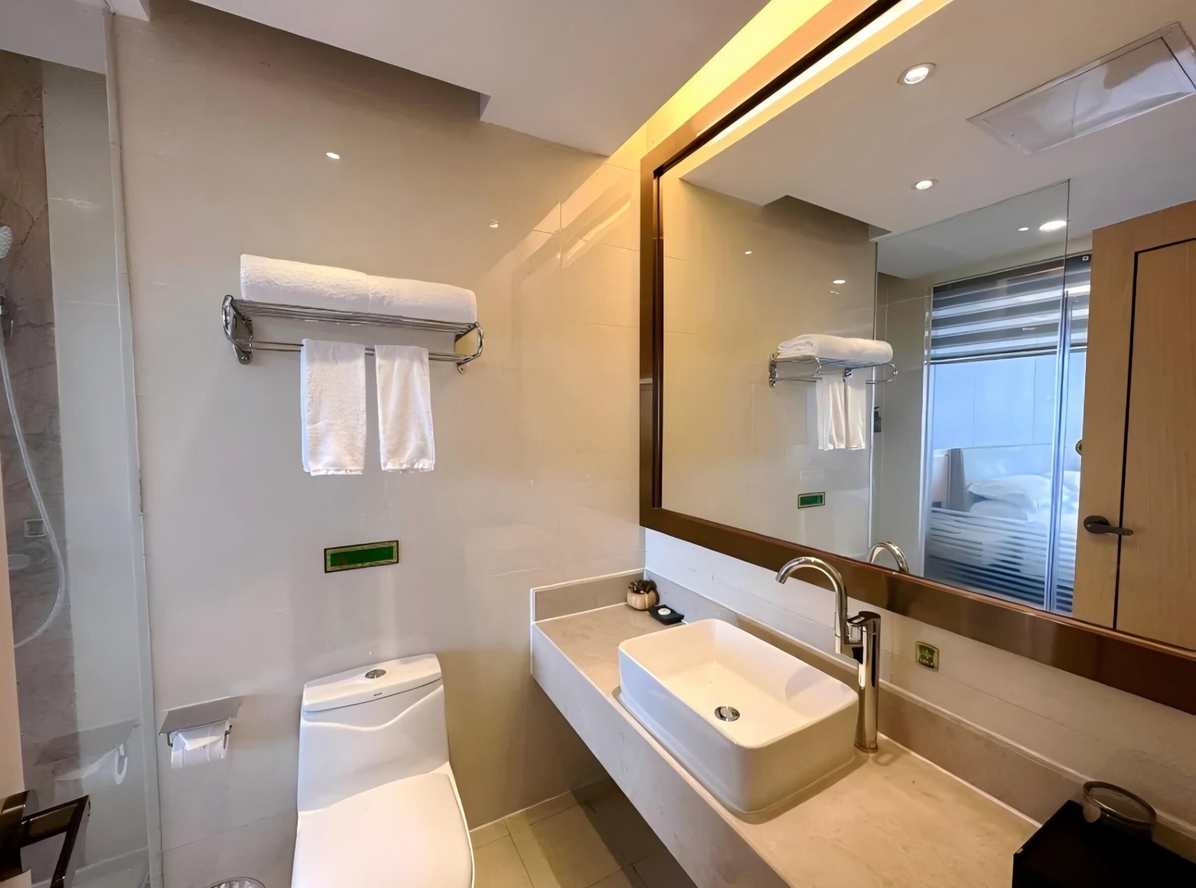 Une salle de bain moderne avec un grand miroir, un lavabo blanc et des toilettes.