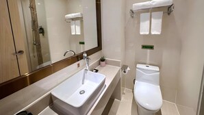 Un baño moderno con un espejo grande, un lavamanos, un inodoro y un perchero para toallas.