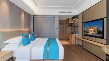 Une chambre d’hôtel moderne dotée d’un grand lit, d’un téléviseur à écran plat, d’un plancher en bois et offrant une vue sur un bâtiment situé à l’extérieur.