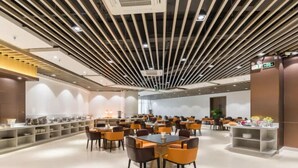 Un comedor amplio con múltiples mesas y sillas, un diseño moderno de techo y un ambiente limpio y bien iluminado.