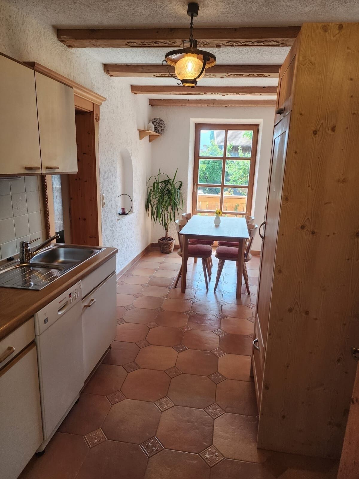A kitchen with a wooden countertop, a sink, and a dining area with a table and chairs.
