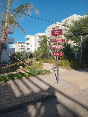 Placa de rua com indicações para Fumba Town, Yana Garden Bakes, Área da Fonte e Toc.