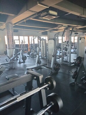 Uma academia com diversos equipamentos de ginástica, incluindo aparelhos de musculação e pesos livres.