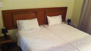 Habitación estándar de hotel con cama doble, dos mesitas de noche y cabecera.