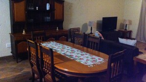 Un comedor con una mesa de madera, sillas, un televisor y un armario.