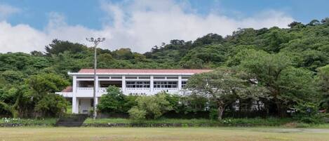 A building with a red roof and white walls, surrounded by lush greenery and trees.