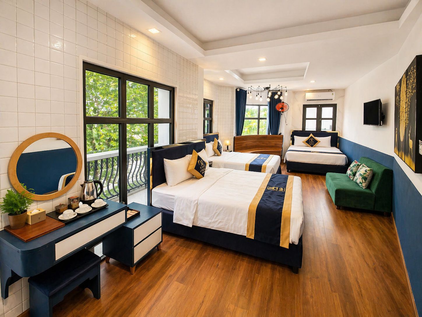 A hotel room with two beds, a desk, a green sofa, a balcony with a view, and a large window.