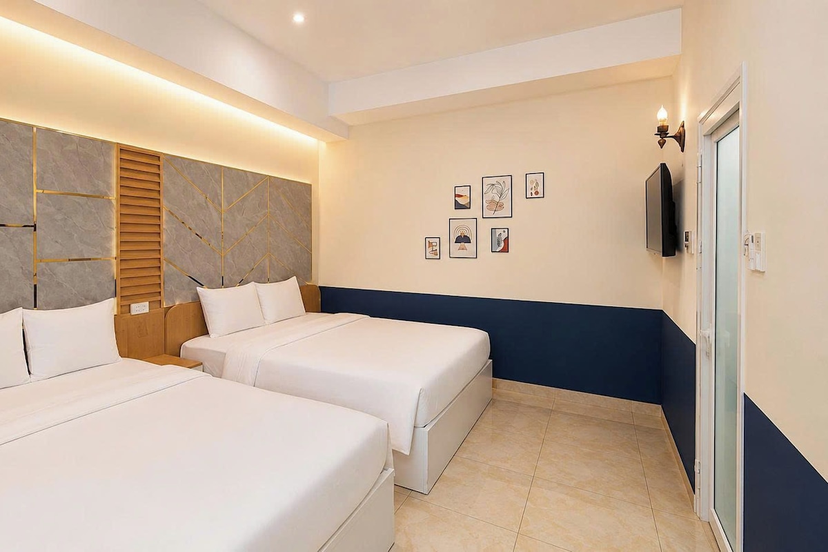 Una habitación de hotel con dos camas, un televisor de pared y obras de arte.