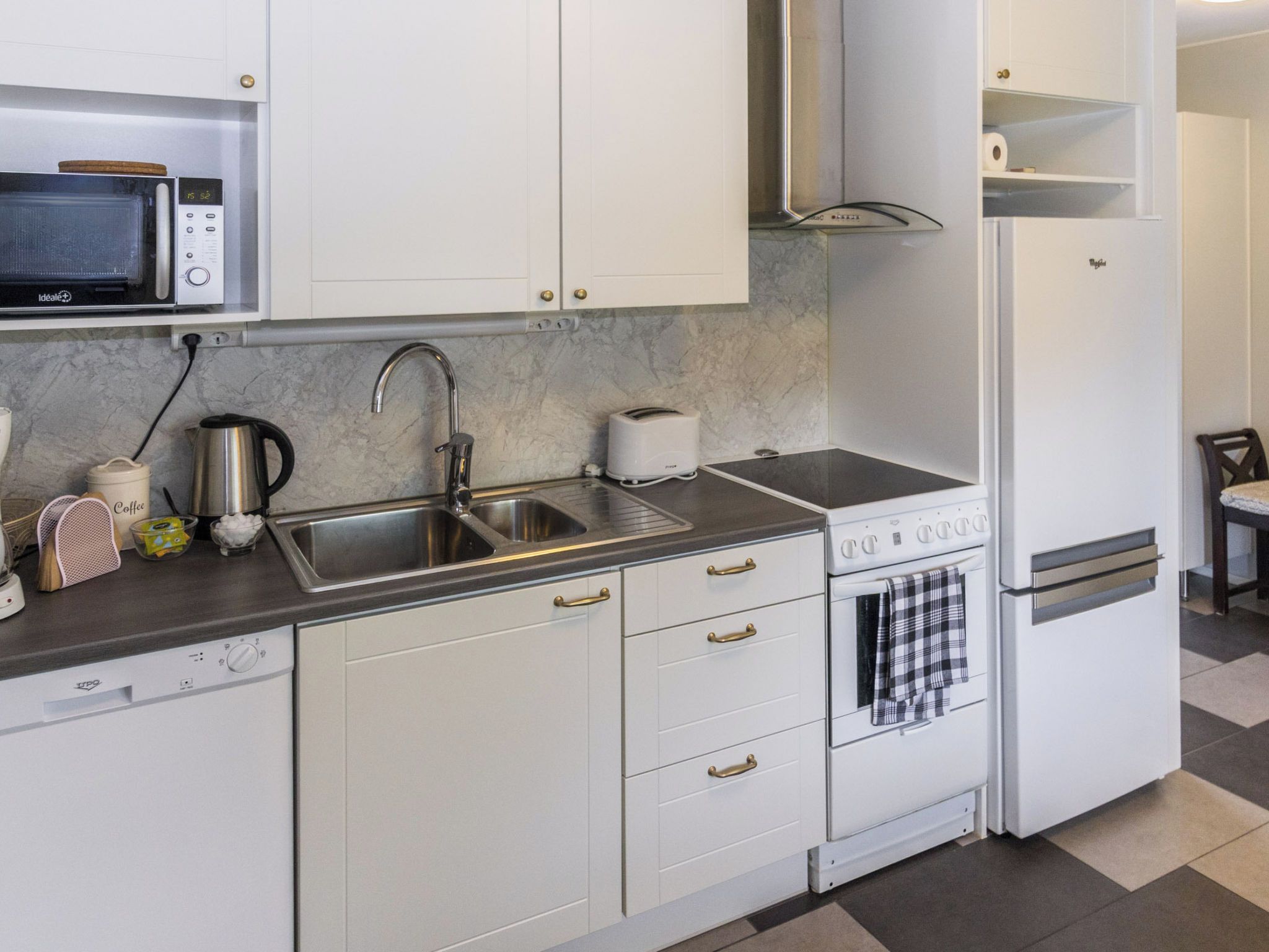 A compact kitchen with a microwave, sink, toaster, and a small oven.