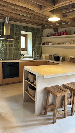 A kitchen with a central island, wooden stools, a built-in oven, and a tiled backsplash. - Character house near the river in Boussy (Boussy-Saint-Antoine)