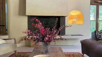 A living room with a fireplace, a sofa, a coffee table with candles, and a vase of flowers.