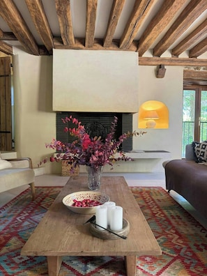 A living room with a fireplace, a sofa, a coffee table with candles, and a vase of flowers. - Character house near the river in Boussy (Boussy-Saint-Antoine)