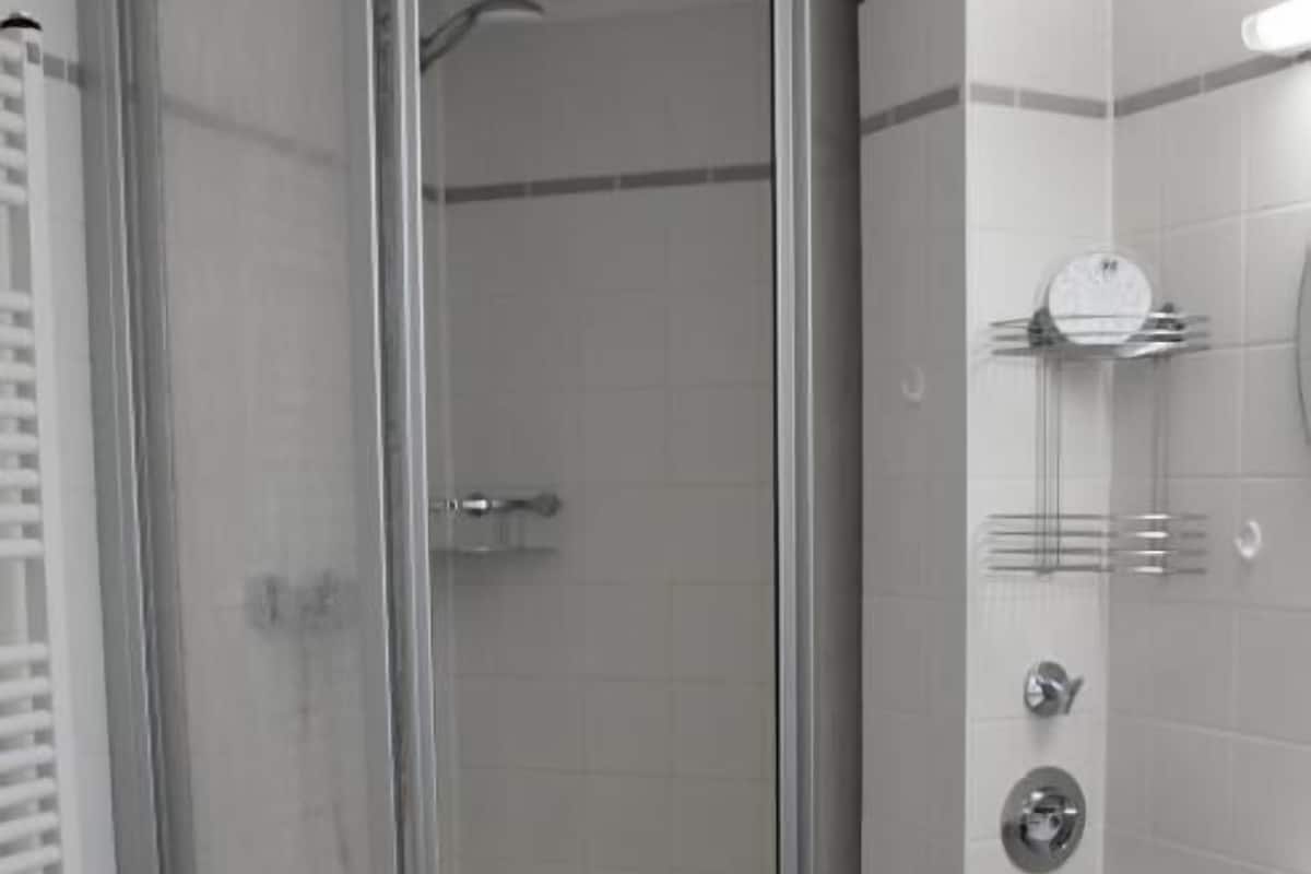 A bathroom with a glass-enclosed shower, a toilet, and a sink.