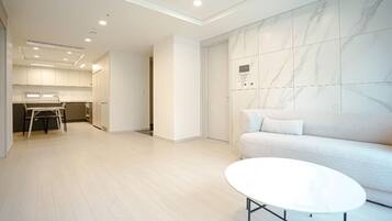 A modern interior with a sofa, a white table, and a kitchen area in the background.