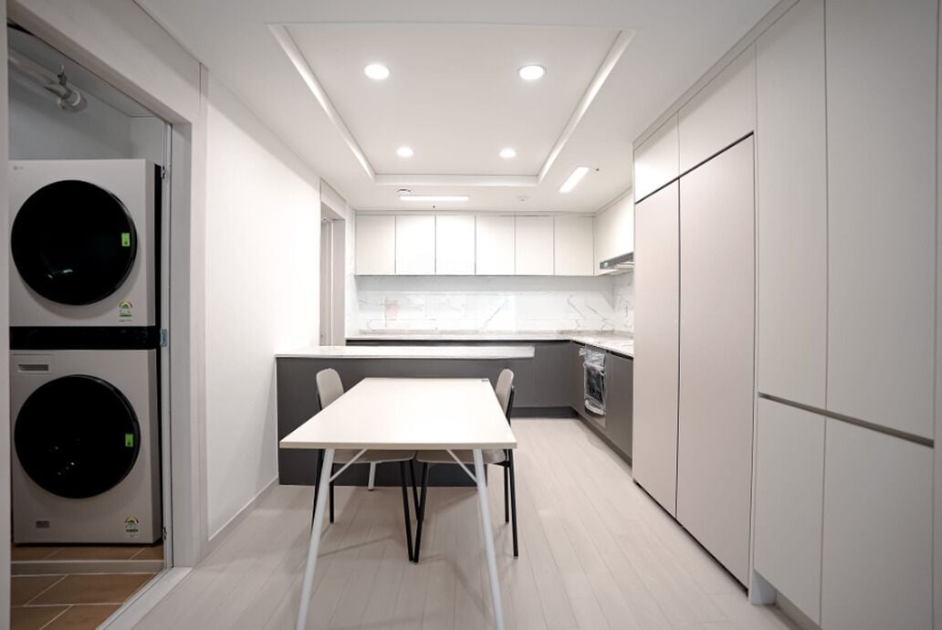 A modern kitchen with built-in appliances, a dining area, and a laundry machine.