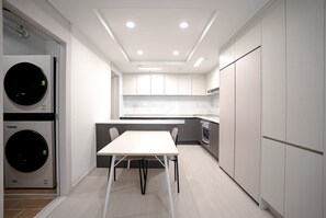 Eine moderne Küche mit eingebauten Geräten, einem Essbereich und einer Waschmaschine.
