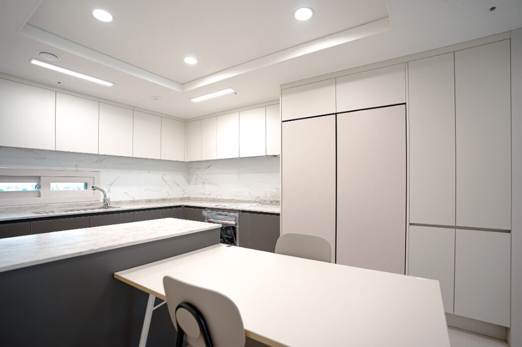 A modern kitchen with white cabinets, a marble countertop, and a built-in dishwasher.