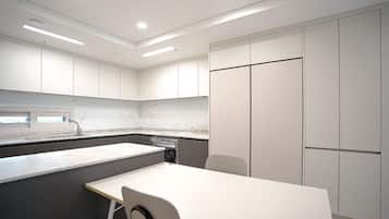 A modern kitchen with white cabinets, a marble countertop, and a built-in dishwasher.