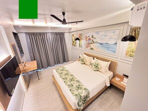 Et hotelværelse med seng, skrivebord, ventilator i loftet og billedkunst på væggene.