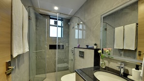 A modern bathroom with a glass-enclosed shower, a toilet, and a sink with a mirror above. - Westside Studio & Apart Hotel (Hyderabad)