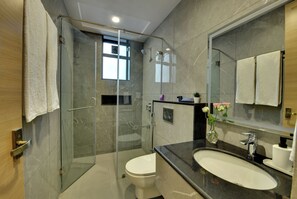 A modern bathroom with a glass-enclosed shower, a toilet, and a sink with a mirror above. - Westside Studio & Apart Hotel (Hyderabad)