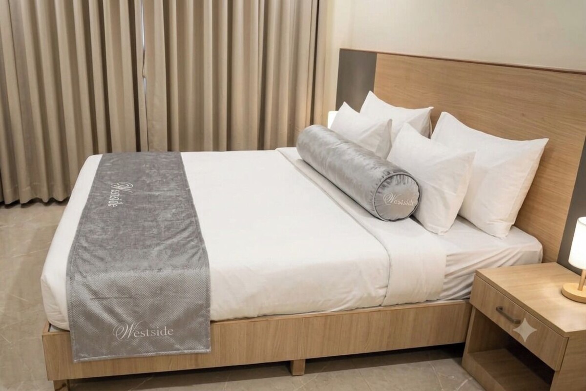 A neatly made bed with a grey blanket, white pillows, and a wooden headboard.