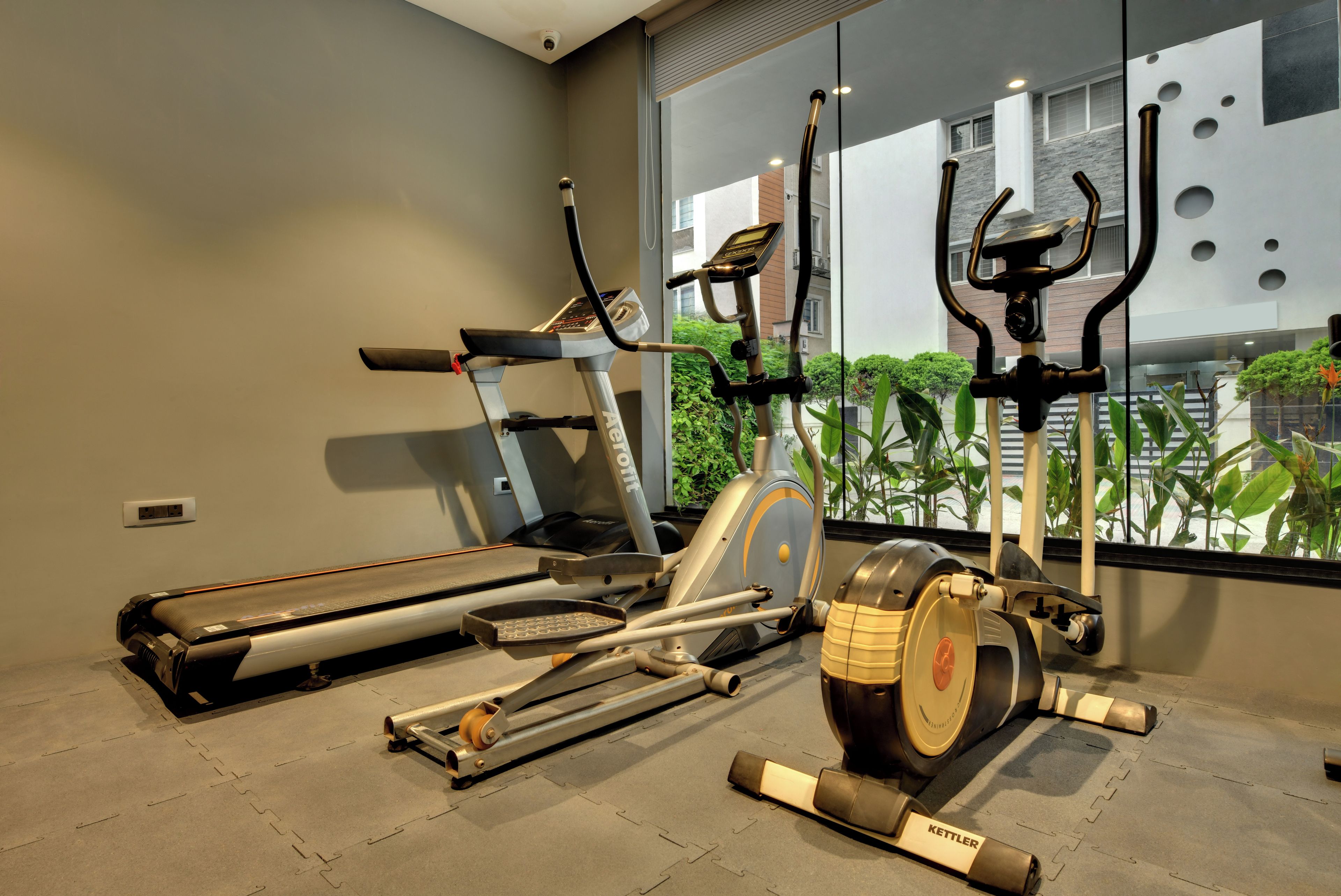Une salle de sport équipée d’un tapis de course, d’un vélo elliptique et d’un vélo d’appartement.
