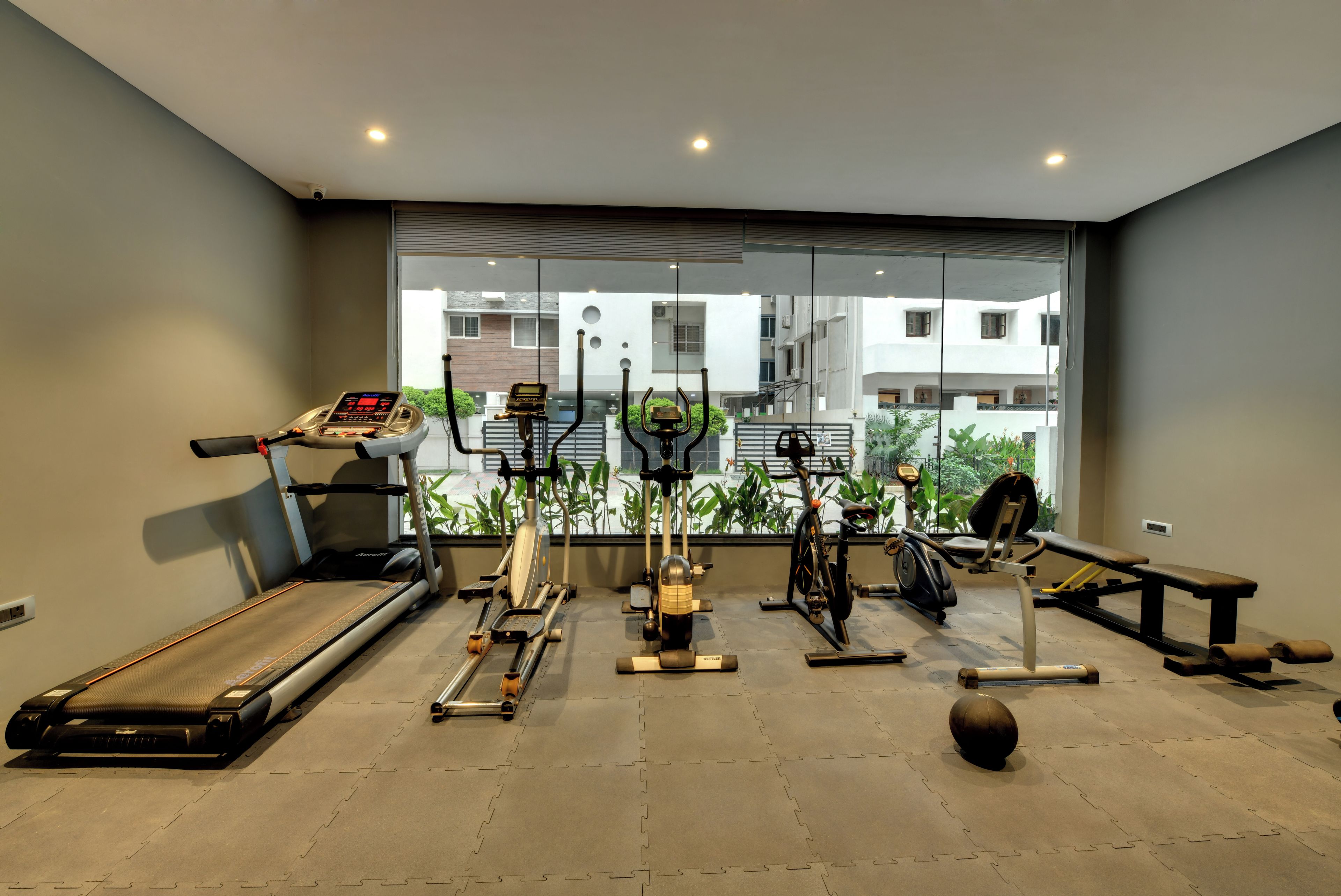 Un gimnasio con cinta de correr, elíptica, bicicleta estática y pesas.