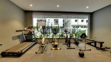 Un gimnasio con cinta de correr, elíptica, bicicleta estática y pesas.