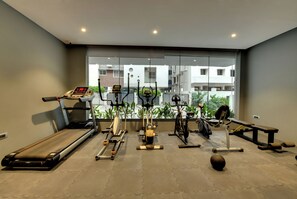 Un gimnasio con cinta de correr, elíptica, bicicleta estática y pesas.