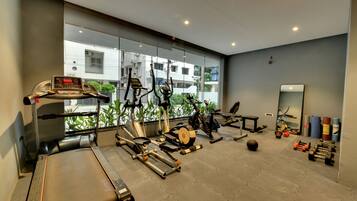 Een fitnessruimte met cardioapparatuur, losse gewichten en een spiegel.