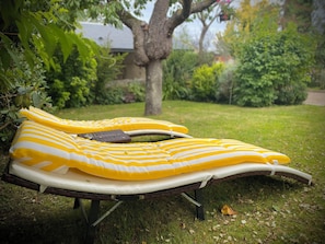 An inflatable mattress on a stand in a grassy area with trees and a house in the background.