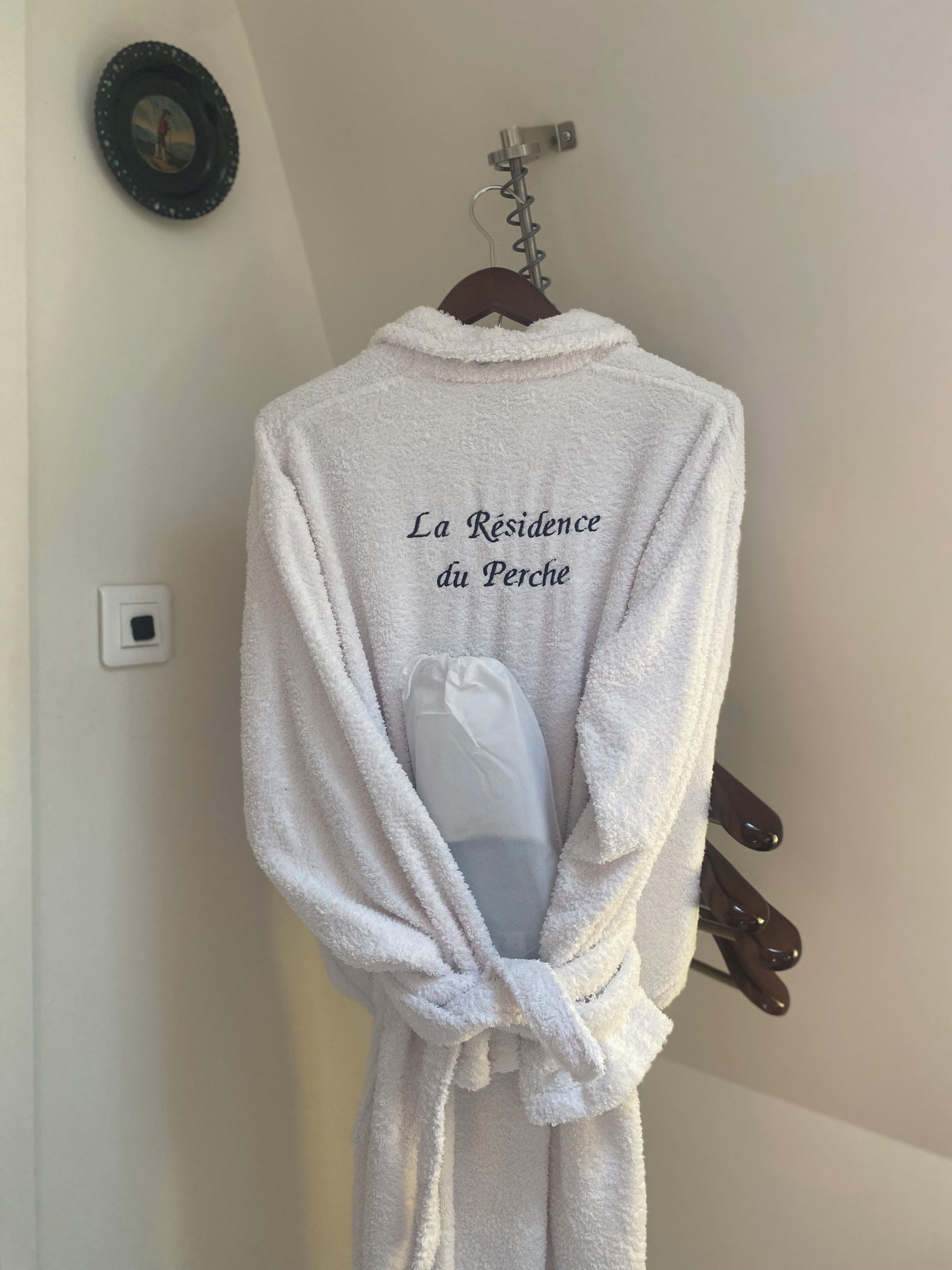 Une tunique blanche avec du texte, accrochée à un mur.