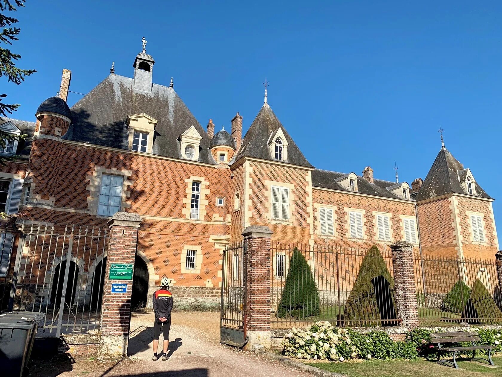 Een historisch gebouw met een bakstenen gevel, meerdere schoorstenen en een hekwerk.