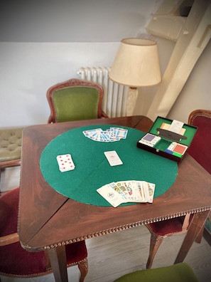 A wooden table with a green felt surface, a lamp, and playing cards.