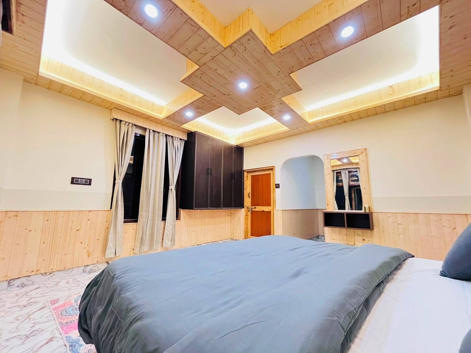 A bedroom with a large bed, wooden ceiling, and a wardrobe.