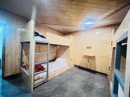 Una habitación con literas, un estante pequeño y una ventana.