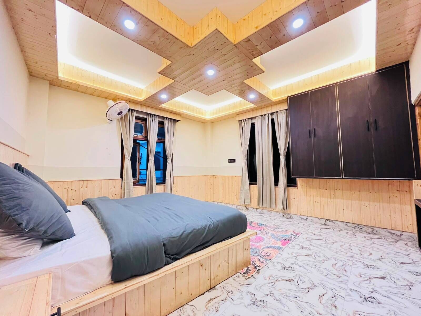 A bedroom with a bed, wooden ceiling, and a wardrobe.