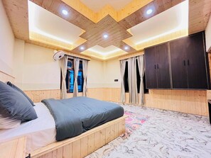 A bedroom with a bed, wooden ceiling, and a wardrobe. - Man Mauji Villa (Kasol)