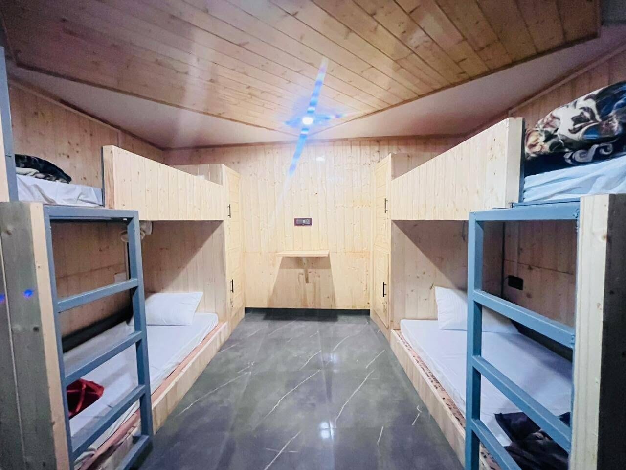 Una habitación con literas, techo de madera y una ventana pequeña.