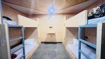 Una habitación con literas, techo de madera y una ventana pequeña.