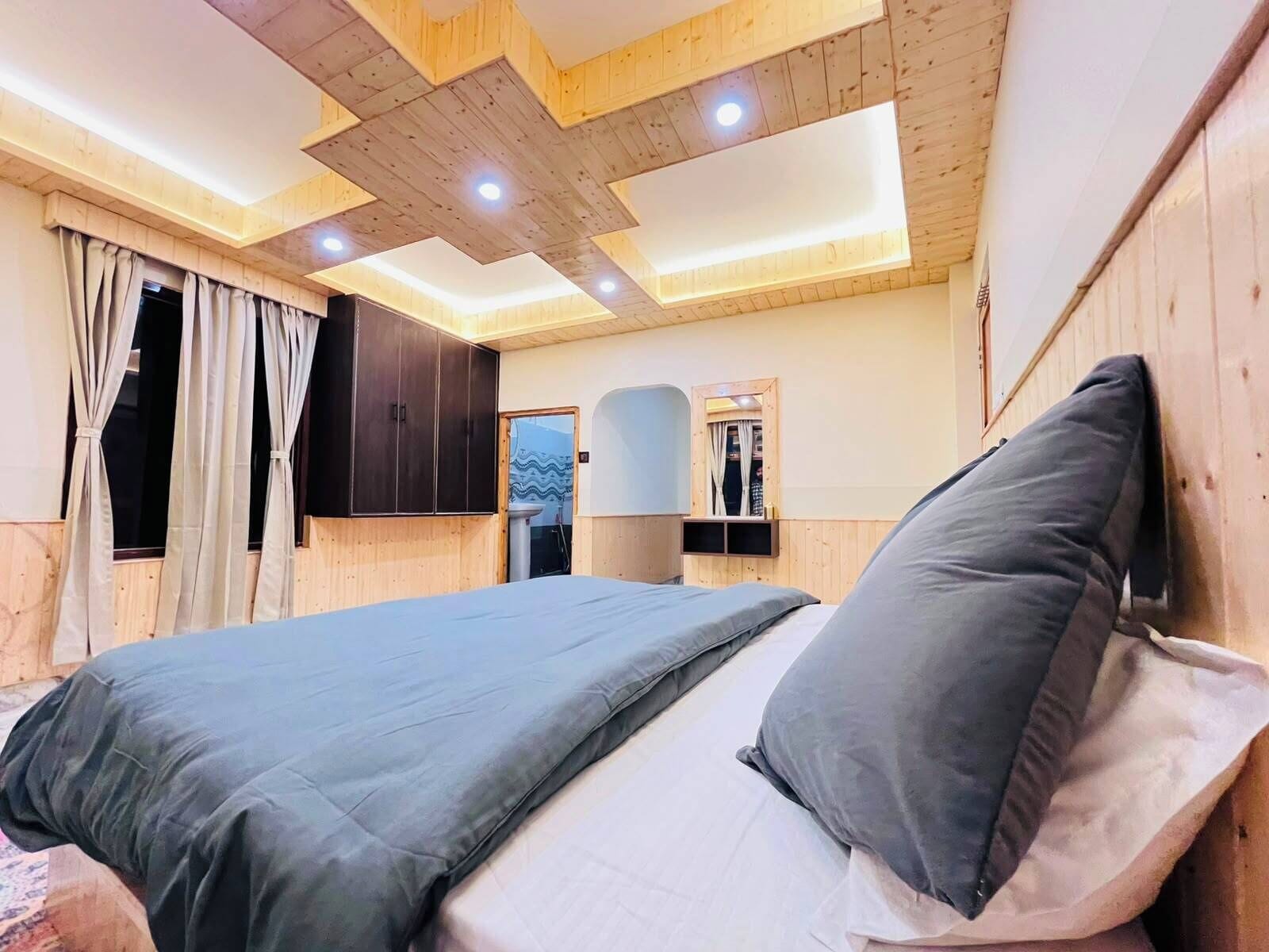 A bedroom with a bed, curtains, a wardrobe, and a mirror.