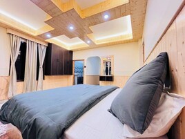 A bedroom with a bed, curtains, a wardrobe, and a mirror.