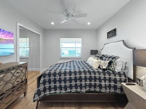 Ein Schlafzimmer mit Bett, Deckenventilator, Fenster und Kommode.