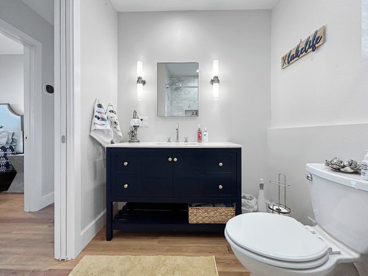 A bathroom with a dark-colored vanity, a white toilet, and a mirror above the sink.
