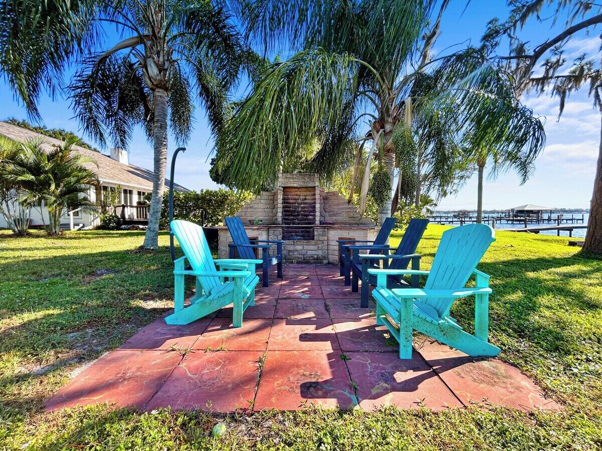 Un patio con cuatro sillas Adirondack turquesas dispuestas alrededor de una chimenea de piedra.
